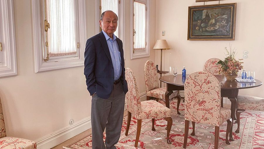 Francis Fukuyama con las manos en los bolsillos en medio de un salón.