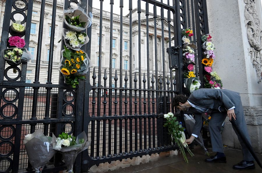 Un hombre deja flores a las puertas del Palacio de Buckingham después de conocerse la noticia de la muerte de Isabel II
