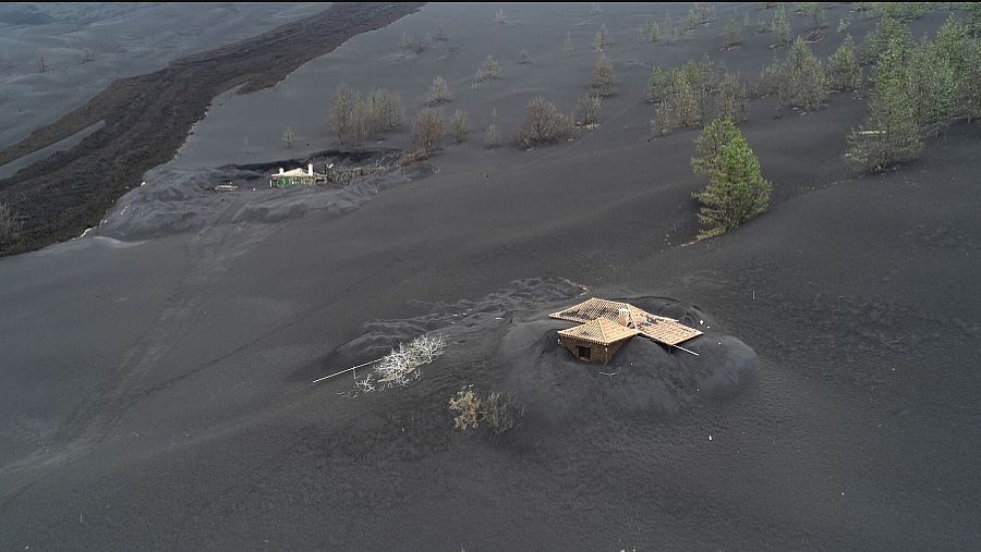 Imagen de dos casas semienterradas a solo unos metros de la colada del volcán