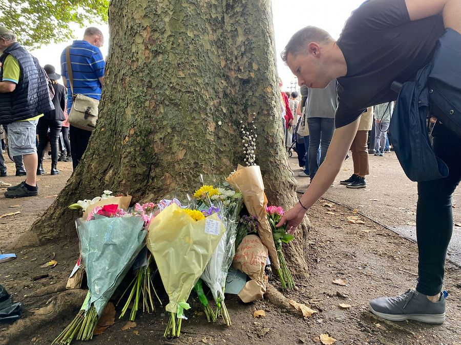 Una persona deja un ramo de flores en los alrededores de Buckingham