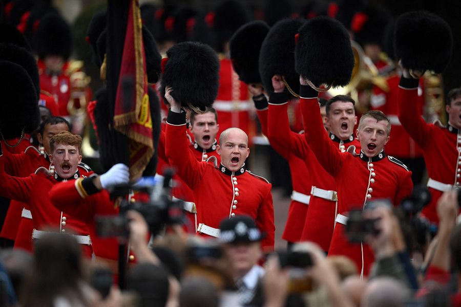 Los miembros de la Guardia de Coldstream levantan sus sombreros de piel de oso mientras saludan al nuevo Rey