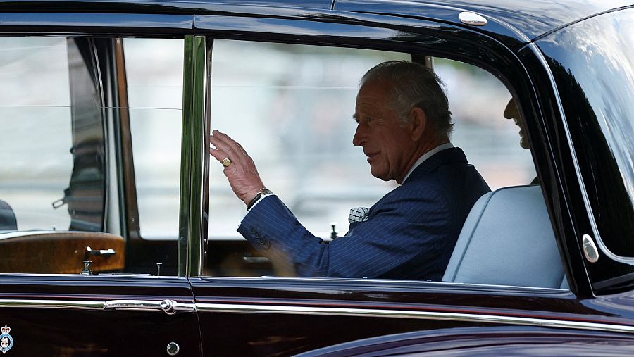 Carlos III, rey de Inglaterra, saluda desde su coche a las puertas del palacio de Buckingham.