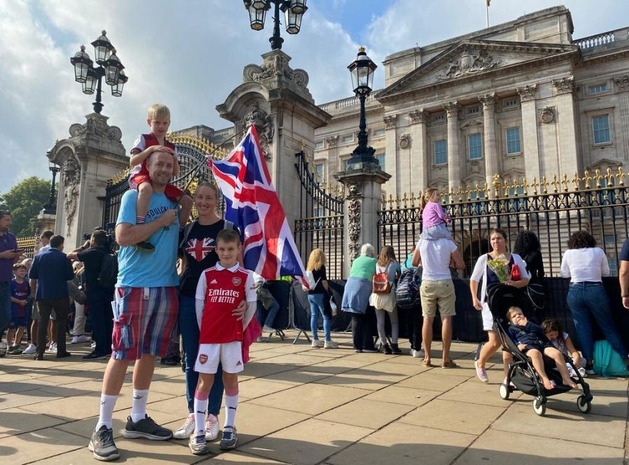 Sarah posa junto a su familia y una gran bandera británica frente al Palacio de Buckingham