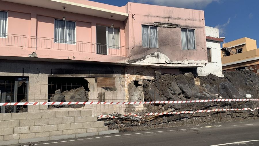 Imagen de una casa con restos de rocas volcánicas que entran en su interior.