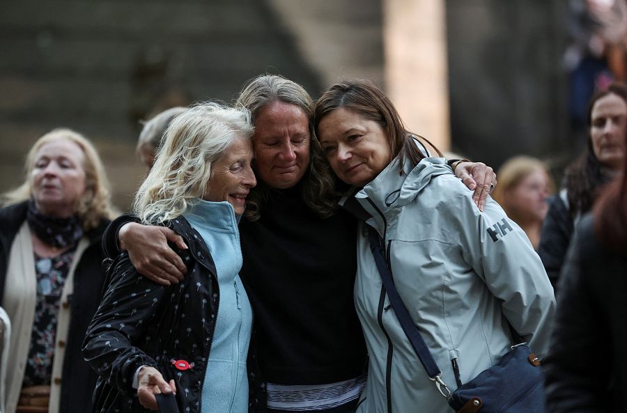 Un grupo de personas se abraza después de mostrar sus respetos a la reina Isabel II