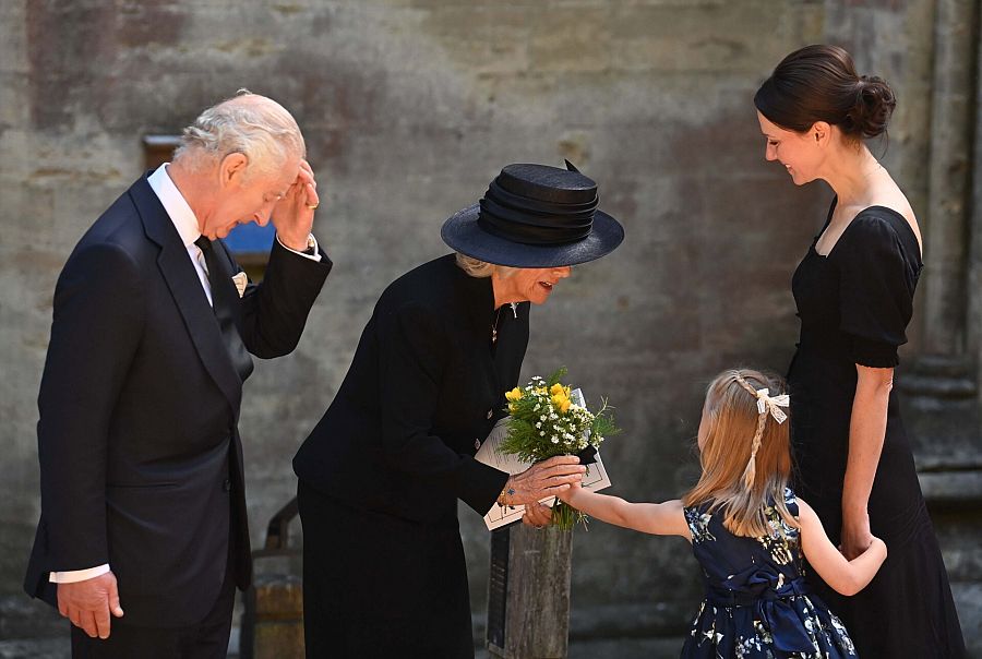 La reina consorte Camilla recibe flores de una niña, frente a la catedral de Llandaff, en Gales