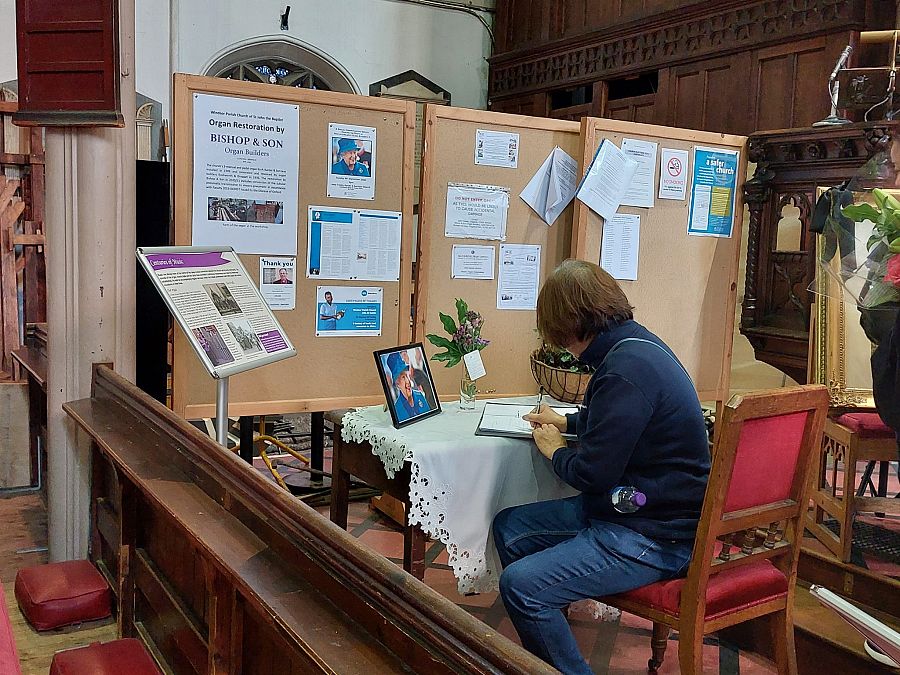 Una mujer firma en el libro de condolencias de la iglesia de San Juan Bautista