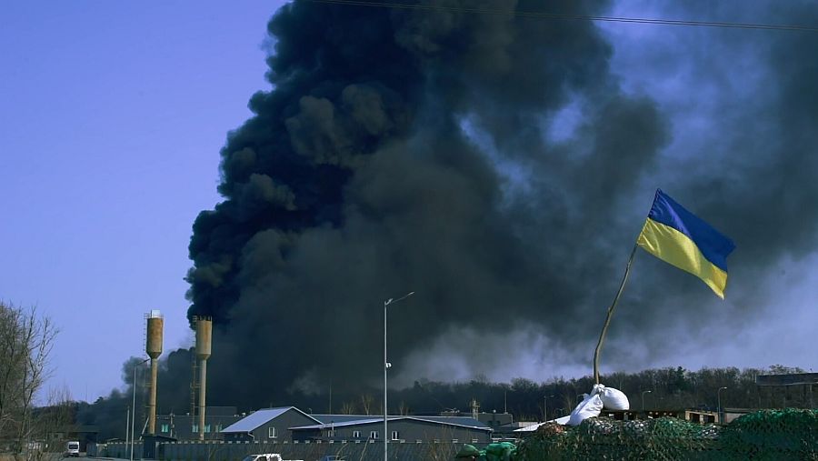 Humo negro en el cielo junto a bandera de Ucrania