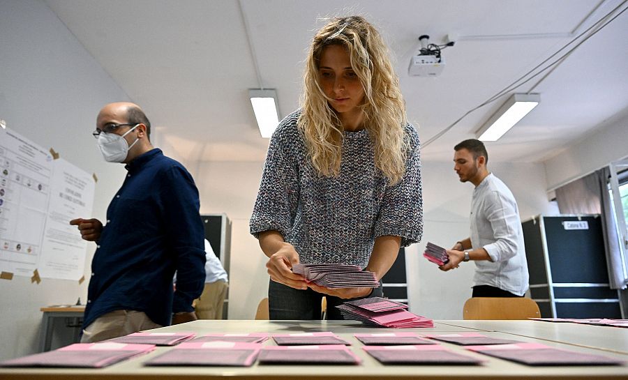 Una mujer prepara papeletas para los votantes en un colegio electoral en Roma