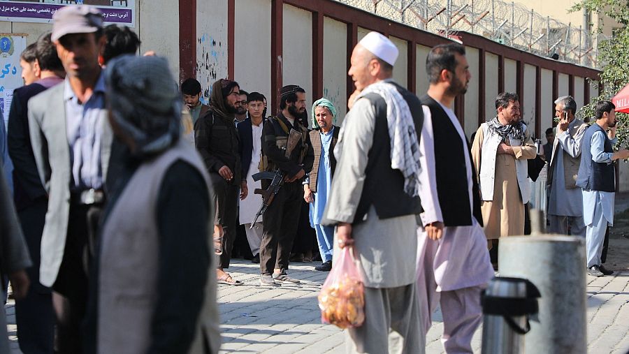 Combatientes talibanes hacen guardia mientras la gente se reúne para buscar a sus familiares fuera de un hospital en Kabul