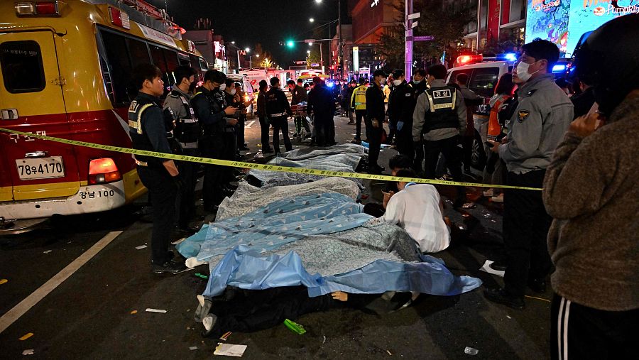 Los cuerpos de varias víctimas permanecen cubiertos tras la estampida en el distrito de Itaewon, en Seúl.