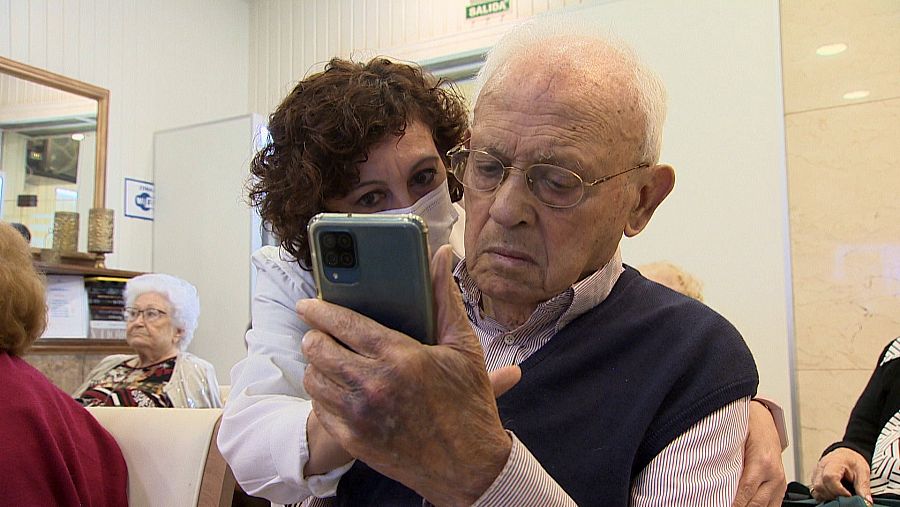 Mujer ayuda a anciano con su teléfono móvil