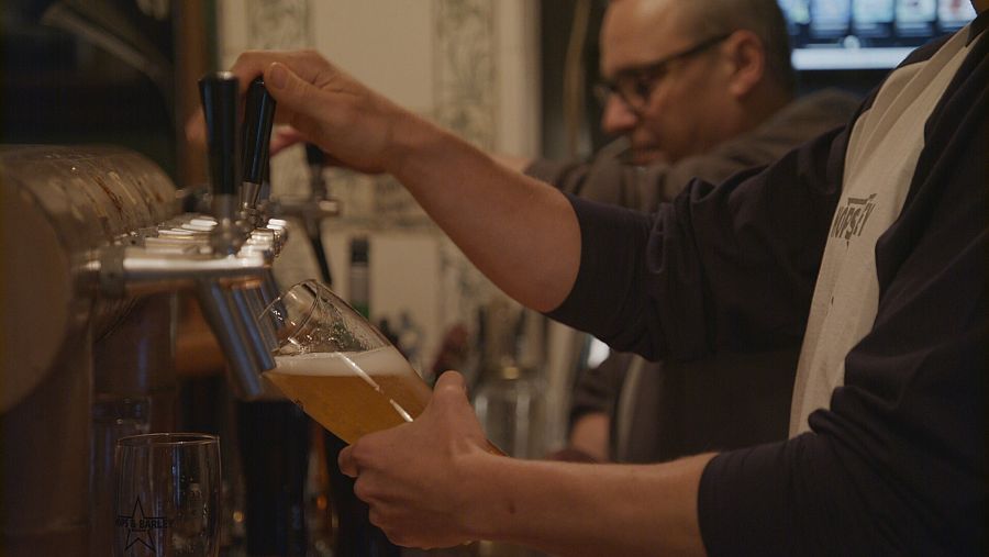 Una mano tira cerveza de gripo en un vaso de cristal