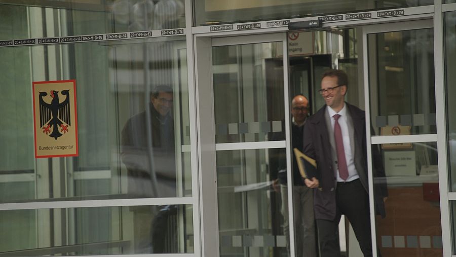 Klaus Muller sale por una puerta de cristal