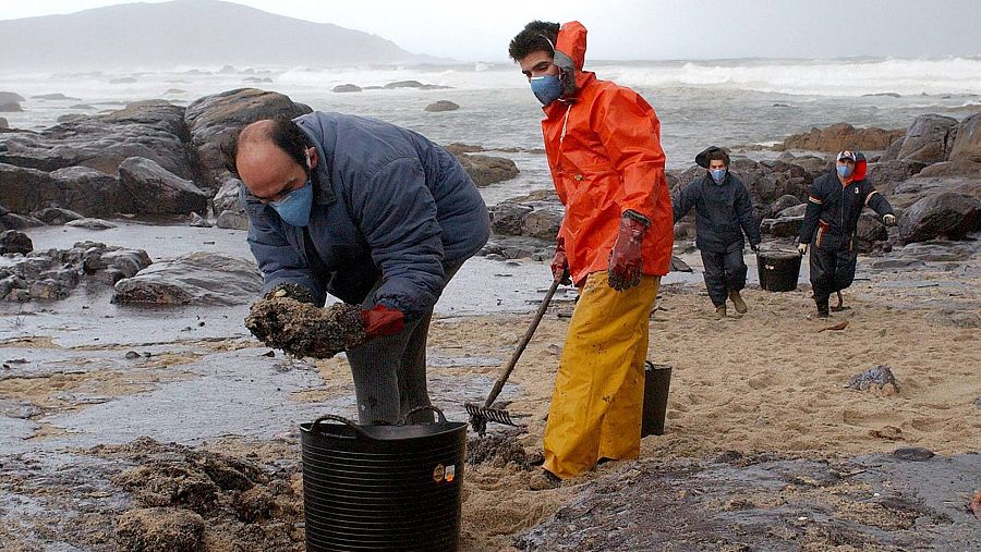 Un grupo de voluntarios realiza labores de limpiado de petróleo en la playa de 