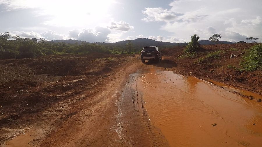 Un coche circula por una carretera completamente embarrada en Ghana