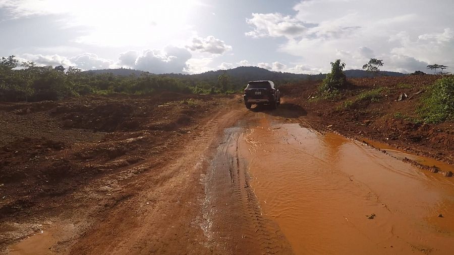 Un coche circula por una carretera completamente embarrada en Ghana