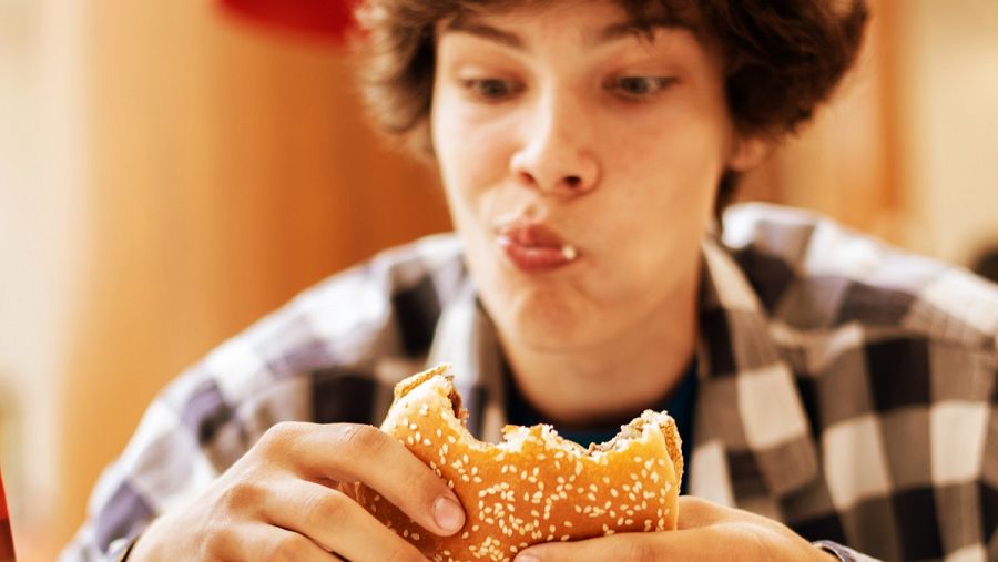 Un joven comiendo una hamburguesa