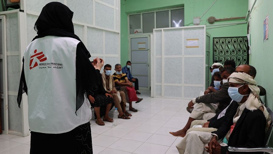 Un grupo de hombres espera en el centro de salud mental de Yemen ante la mirada de un miembro de MSF
