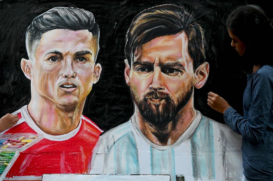 Mundial de Qatar: una estudiante de arte da los últimos retoques a un cuadro de Cristiano Ronaldo y Messi, en Mumbai (India).