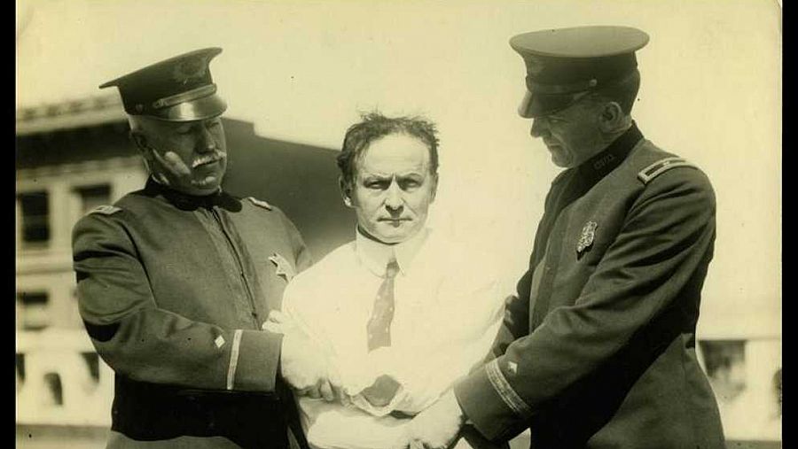 Harry Houdini agarrado por dos agentes de policía