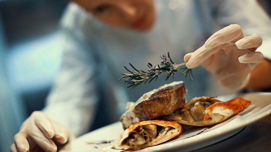 Un cocinero dando el último toque a un plato de alta cocina