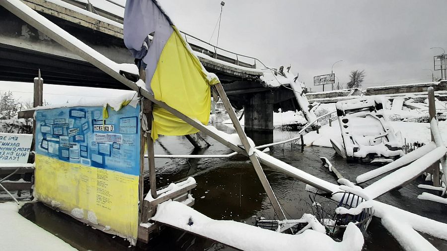 Puente destruido de Irpin con banderas ucranianas y nieve.