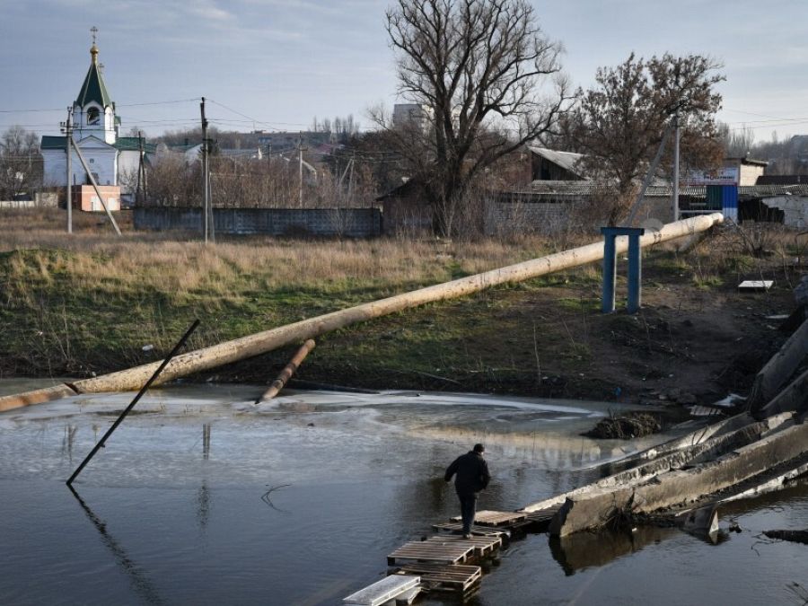 Guerra en Ucrania hoy: un hombre cruza un río sobre los escombros de un puente destruido en Bajmut