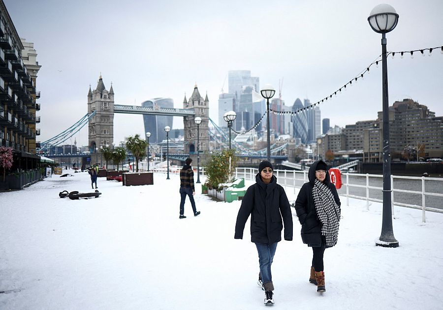 Varias personas caminan por un camino cubierto de nieve cerca del Tower Bridge de Londres, este lunes, 12 de diciembre de 2022