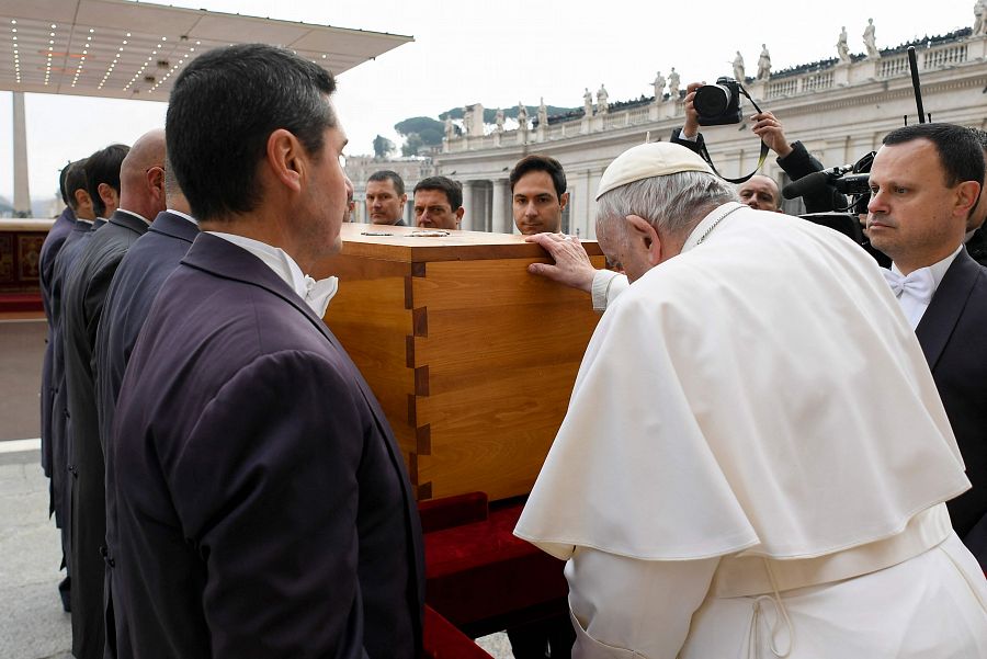 El papa posa su mano sobre el ataúd de Benedicto.