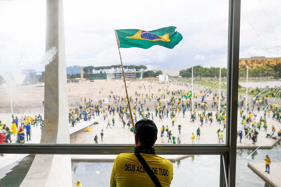 Un hombre ondea una bandera de Brasil desde el interior de uno de los edificios asaltados.