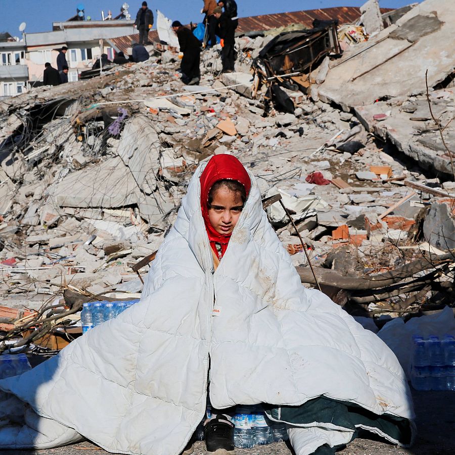 Una niña está sentada al lado de un edificio destruido por el terremoto en Kahramanmaras, Turquía