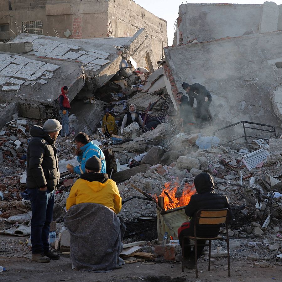 Locales se sientan en frente de los edificios destruidos por el terremoto en Kahramanmaras (Turquía)