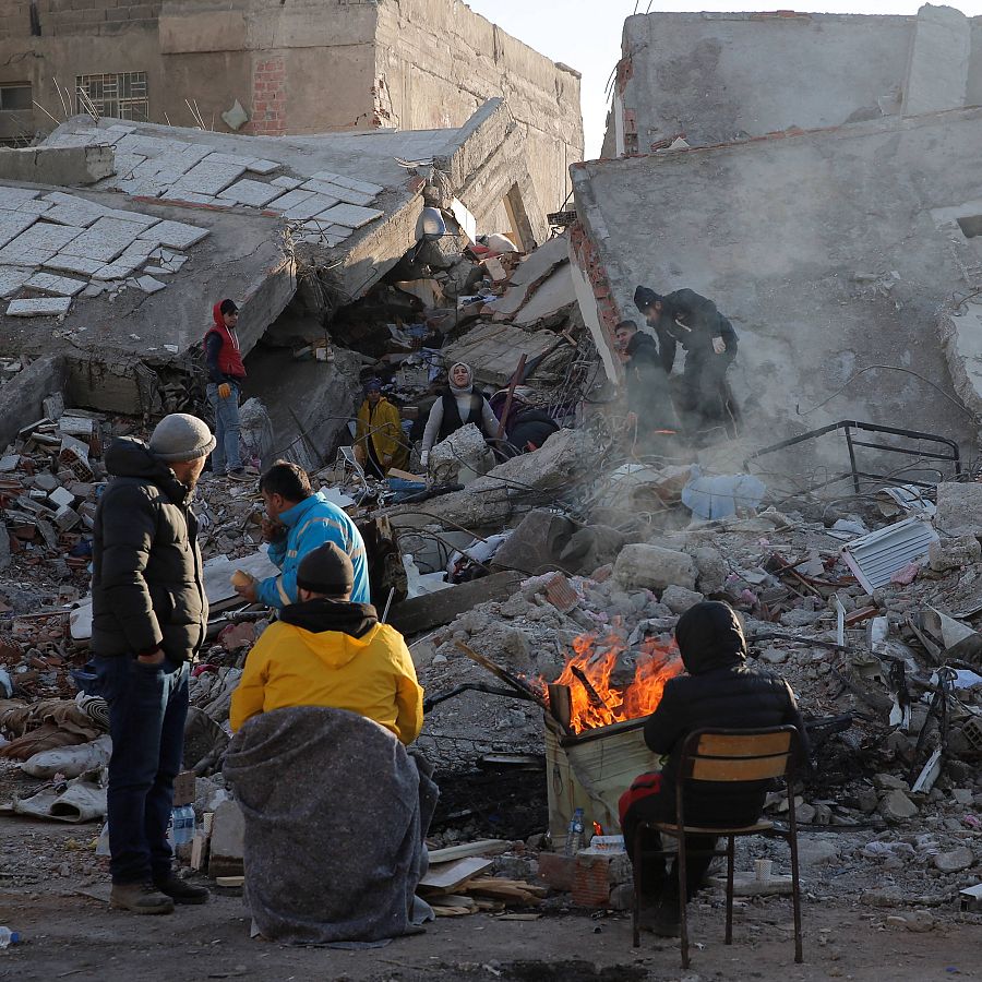 Locales se sientan en frente de los edificios destruidos por el terremoto en Kahramanmaras (Turquía)