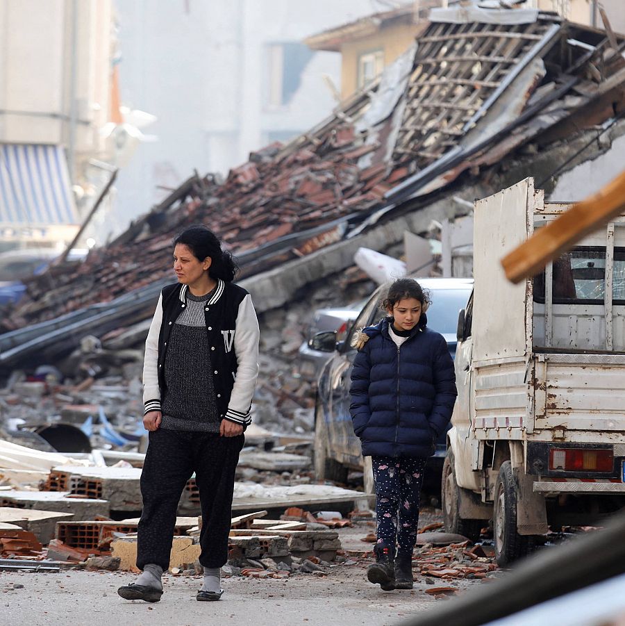 Una mujer y una niña caminan por el paisaje de edificios destruidos por el terremoto que sacudió a Hataym Turquía