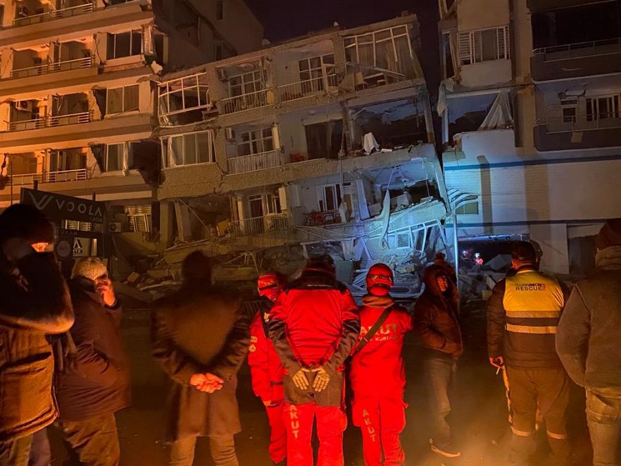 Un equipo de rescate entra en un edificio derrumbado de Iskenderun mientras los vecinos observan su trabajo