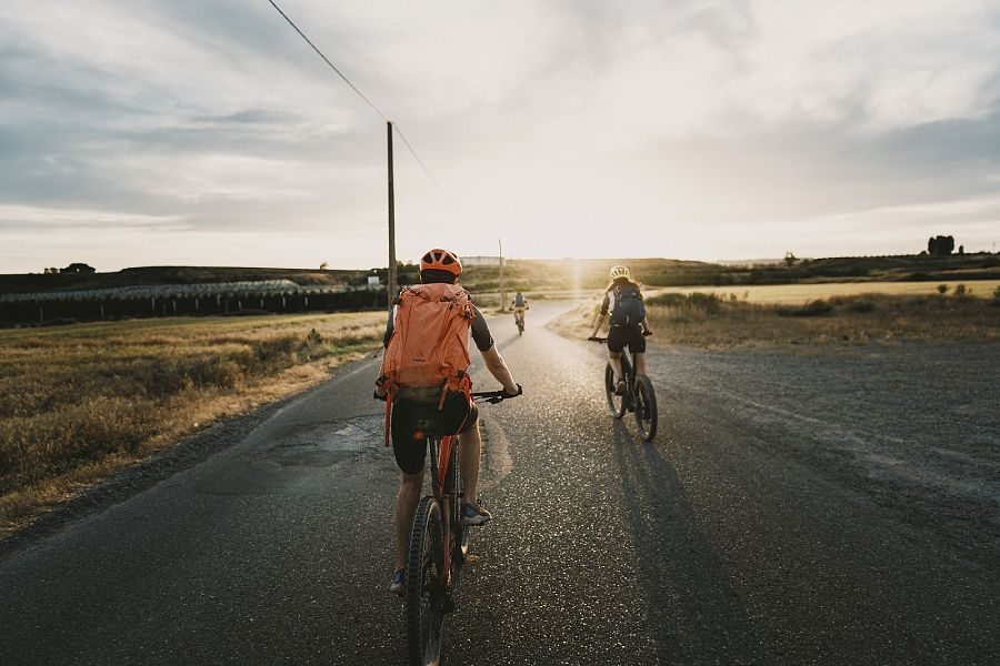 Tres dels aventurers en bicicleta amb la posta de sol al fons