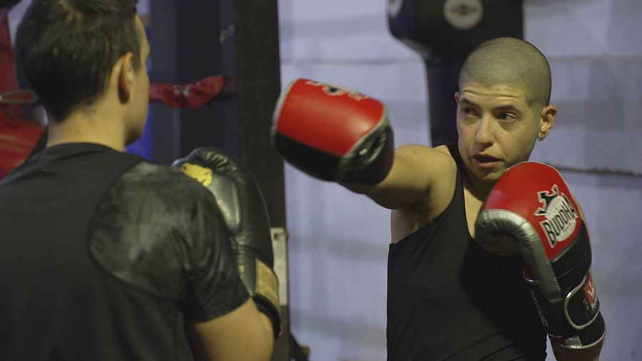 Imagen de hombre trans con pelo afeitado y guantes de boxeo puestos