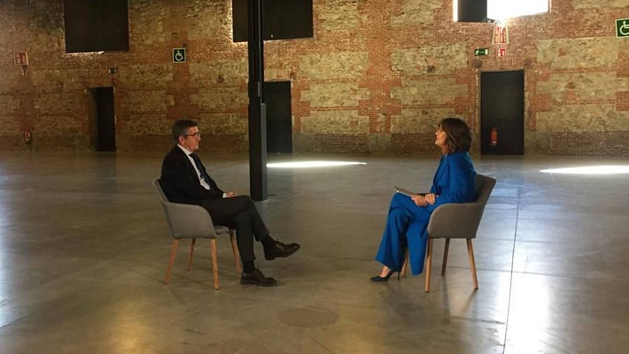 Patxi López y Diana Arias sentados en sendas sillas en una de las naves vacías de El Matadero de Madrid.