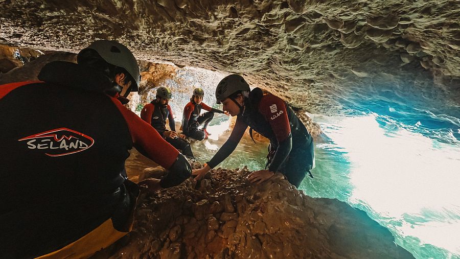 Quatre del sis aventurers descendint per un barranc