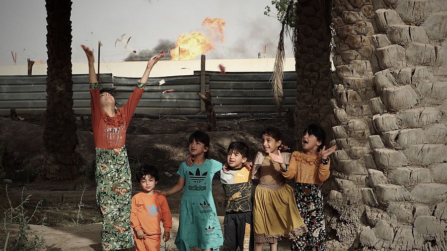 Niñas juegan mientras las antorchas queman gas en el campo petrolífero
