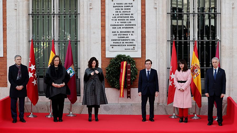 La presidenta de la Comunidad de Madrid, Isabel Díaz Ayuso, y el alcalde de la capital, José Luis Martínez-Almeida, junto a representantes de asociaciones de víctimas, bajo la placa que recuerda a las víctimas del 11M.
