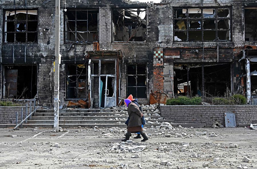 Personas caminan frente a una tienda destruida en el pueblo de Tsirkuny, región de Járkov, en medio de la invasión rusa de Ucrania