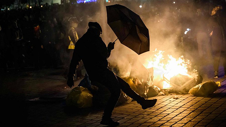 Un manifestante junto a un incendio en una jornada de protestas
