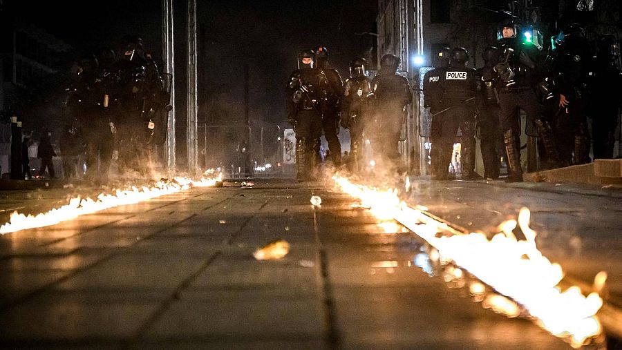 Oficiales de policía junto a un tranvía en llamas