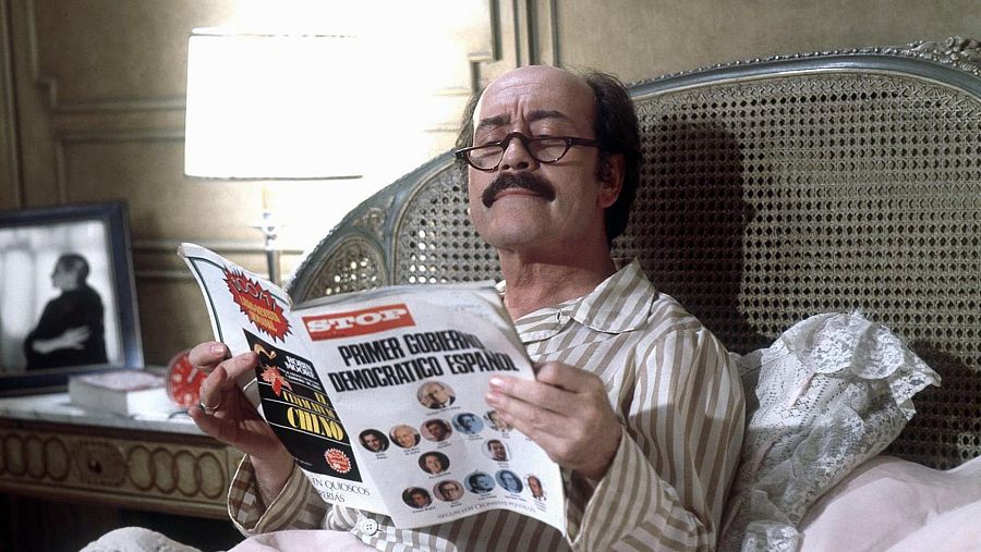 Imagen de José Luis López Vázquez acostado en una cama, leyendo una revista, durante el rodaje de una película