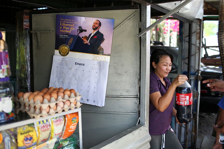 Una mujer vende un refresco en una tienda de La Campanera