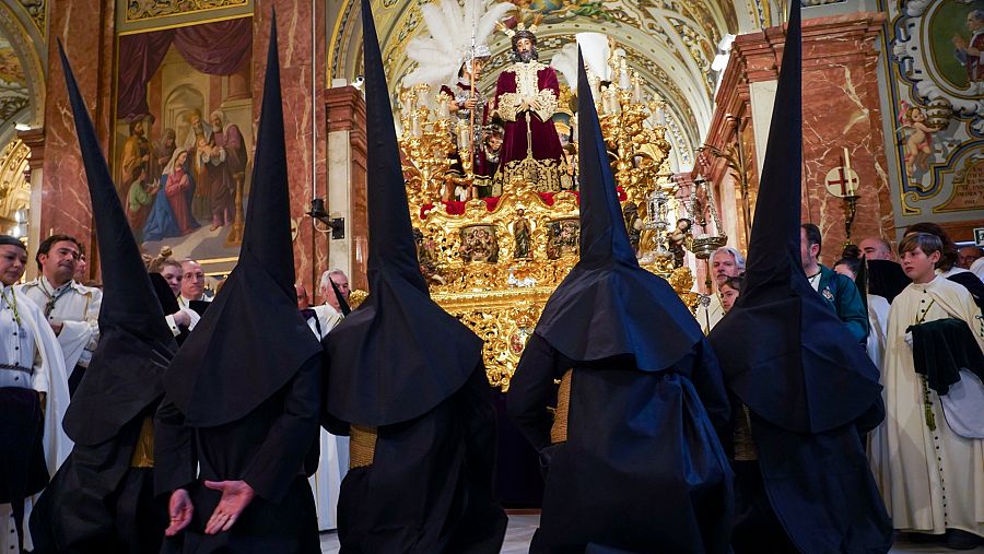 Nazarenos de la hermandad del Gran Poder rezan ante el paso del Cristo de la Sentencia durante la visita a la Basílica de la Macarena