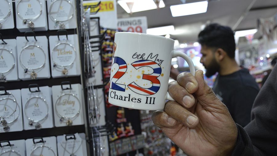 Krishna sostiene una taza que ha comprado a sus nietos para recordar la coronación de Carlos III