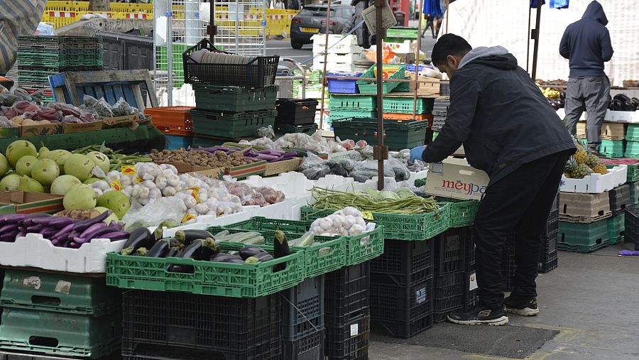 Un hombre coloca fruta en un puesto en el barrio londinense de Tower Hamlets